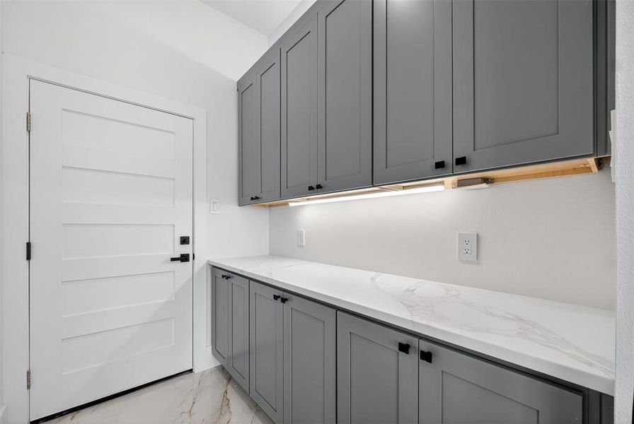 Laundry area featuring light marble finish floors