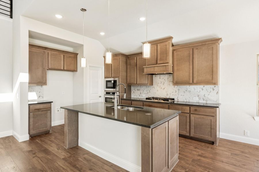 Kitchen with wood cabinets, center island with dark countertop, pendant lights, and hardwood floors Kitchen with wood cabinets, center island with dark countertop, pendant lights, and hardwood floors