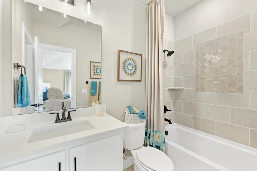 Bathroom with white vanity, tub-shower combo with hexagon tile surround, and large mirror Bathroom with white vanity, tub-shower combo with hexagon tile surround, and large mirror