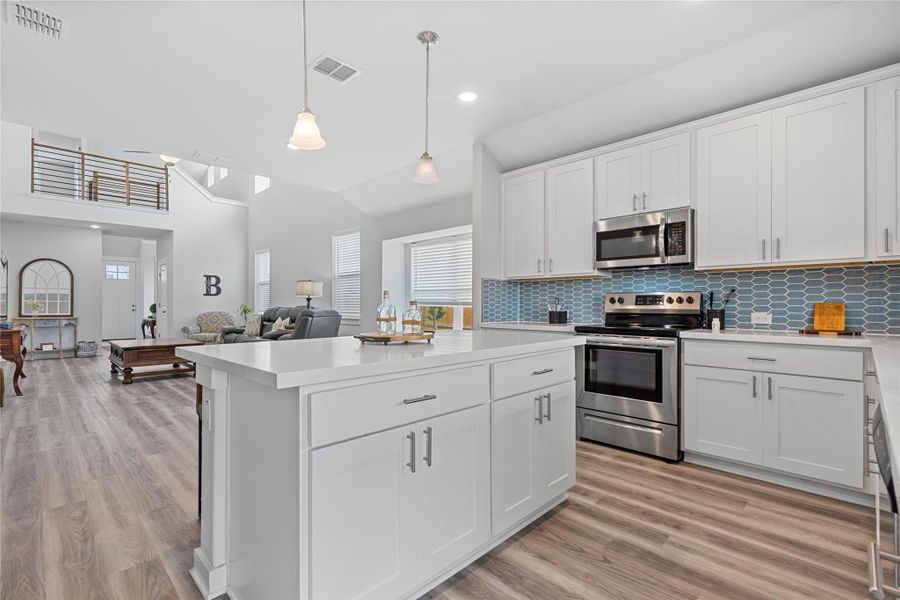 Kitchen with stainless steel appliances, light countertops, light wood-type flooring, white cabinets, and recessed lighting Kitchen with stainless steel appliances, light countertops, light wood-type flooring, white cabinets, and recessed lighting