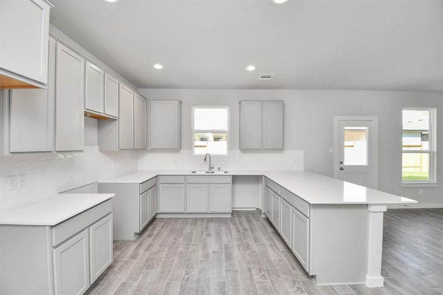 Discover another perspective of this stunning kitchen, generously appointed with an abundance of counter space. Sample photo of completed home with similar floor plan. As-built interior colors and selections may vary.