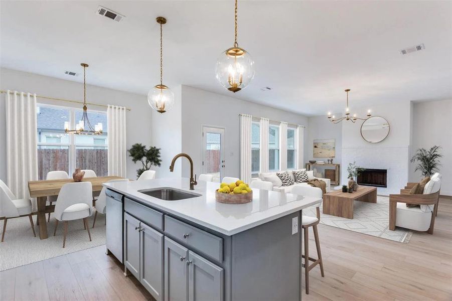 Kitchen with a chandelier, gray cabinetry, a fireplace, and light wood finished floors