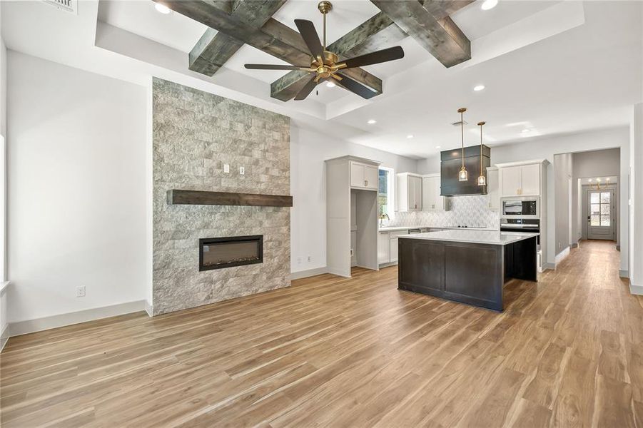Kitchen featuring beam ceiling, open floor plan, decorative light fixtures, a ceiling fan, and coffered ceiling