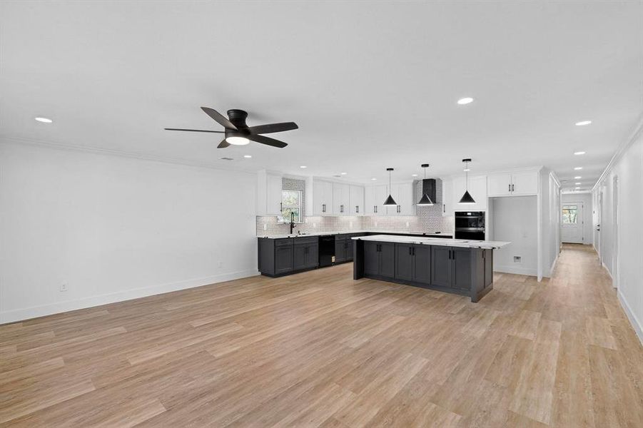 Kitchen with white cabinets, hanging light fixtures, tasteful backsplash, a center island, and recessed lighting