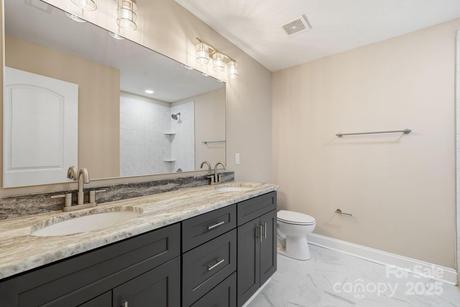 Elegant guest bath with stone countertop and dual vanities. Elegant guest bath with stone countertop and dual vanities.