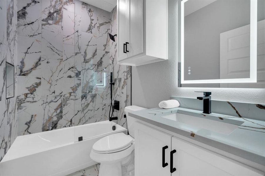 Second full bathroom for secondary bedrooms. Features a combined bath / shower with marble tile.