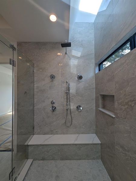 Shower wall with dual hand and wall mount shower heads and a rain head fixture.