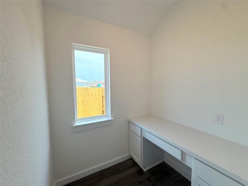 Unfurnished office featuring dark wood-style flooring and built in desk Unfurnished office featuring dark wood-style flooring and built in desk