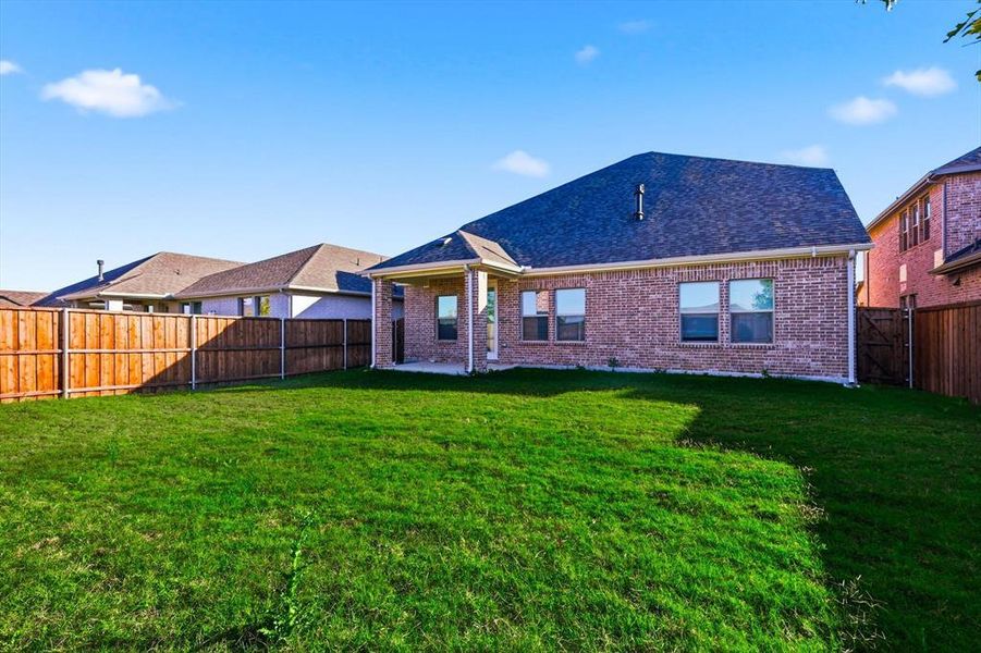 Rear view of property with a patio, brick siding, a fenced backyard, and a shingled roof