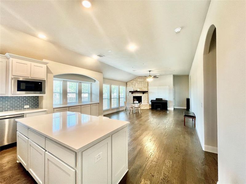 Kitchen with a fireplace, lofted ceiling, black microwave, and dark hardwood / wood-style floors