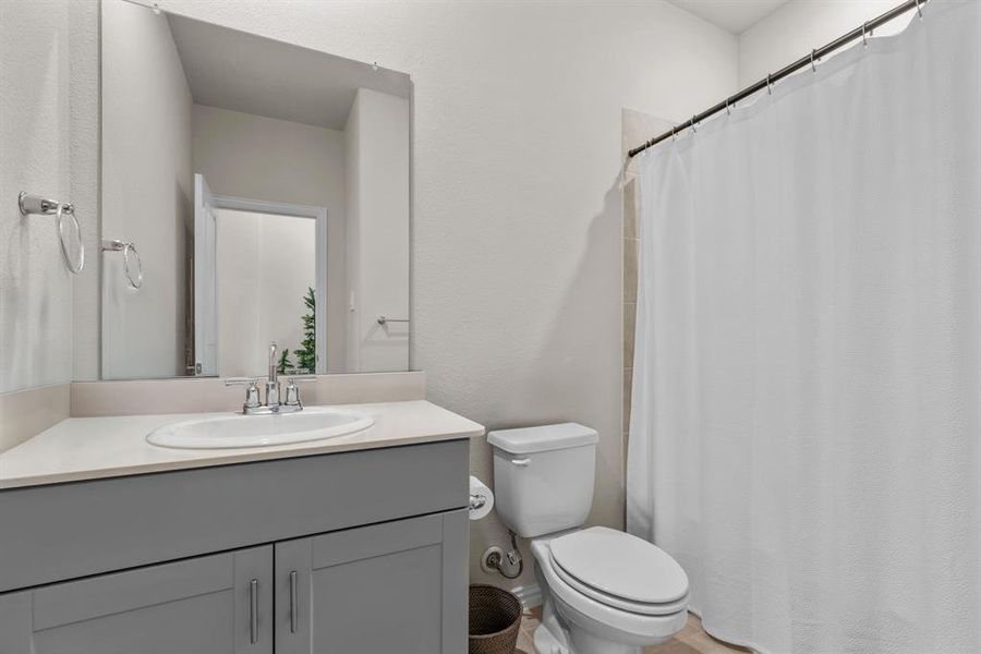 Full bathroom featuring vanity, curtained shower, and a textured wall Full bathroom featuring vanity, curtained shower, and a textured wall