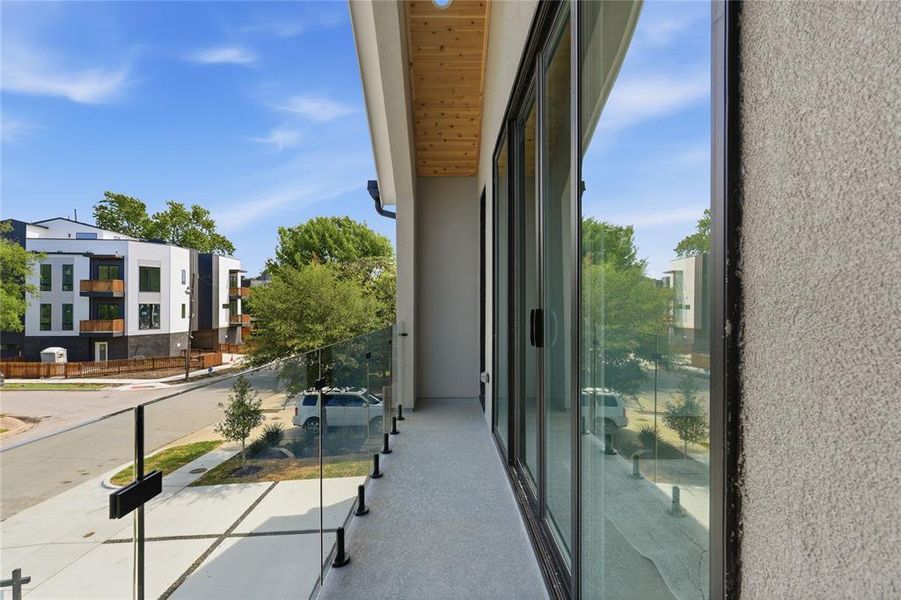 Private balcony featuring glass railings, a concrete surface, and a wood-finish soffit