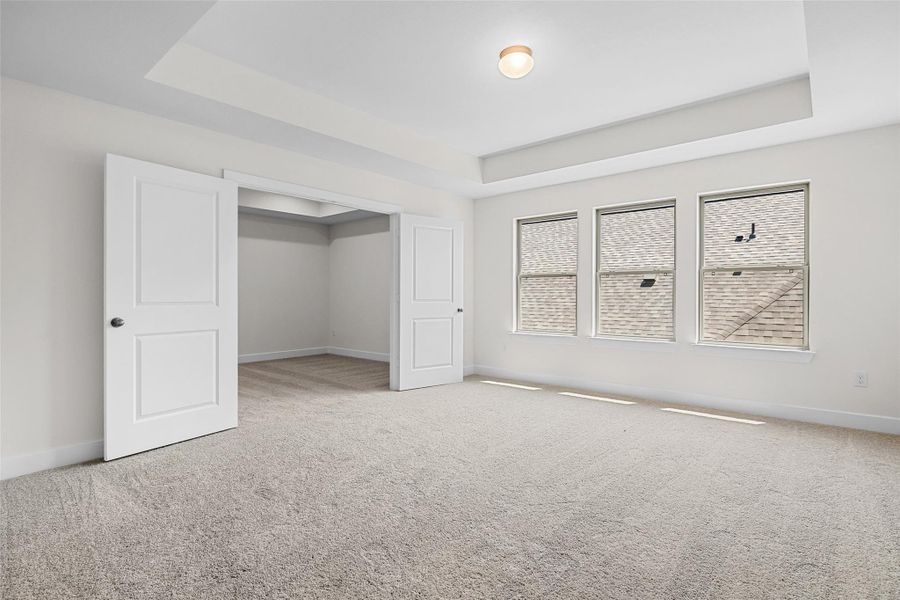 Unfurnished bedroom with a raised ceiling and carpet floors Unfurnished bedroom with a raised ceiling and carpet floors