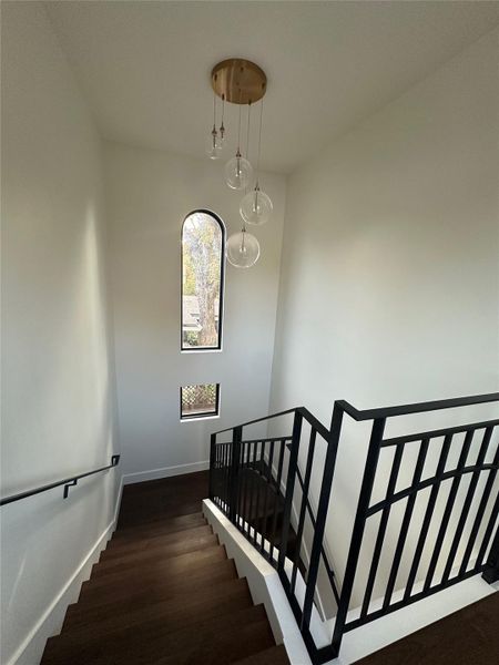 Staircase featuring dark wood-finish treads, a custom black metal railing, and white risers