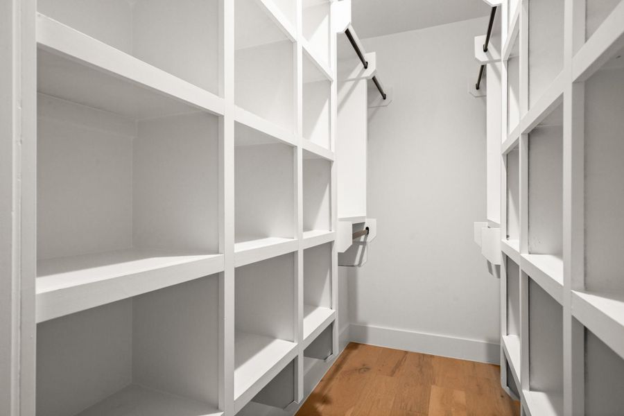 Walk in closet in the primary bedroom featuring wood finished floors
