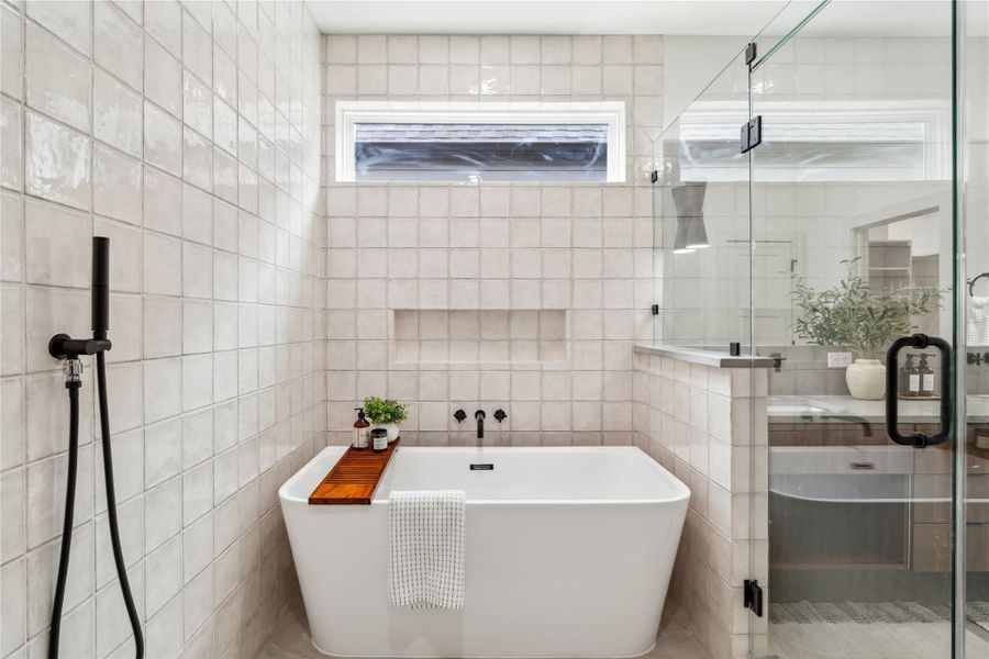 Treat yourself to everyday luxury with a deep soaking tub set beneath a privacy window—perfectly framed by handcrafted tile and thoughtful niches to keep your moment of peace clutter-free.