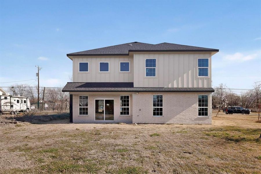 Back of house featuring a lawn, board and batten siding, a shingled roof, and brick siding Back of house featuring a lawn, board and batten siding, a shingled roof, and brick siding