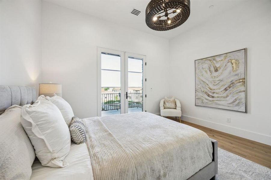 Guest suite on main level with access to balcony, French doos, wood finished floors, and baseboards Guest suite on main level with access to balcony, French doos, wood finished floors, and baseboards