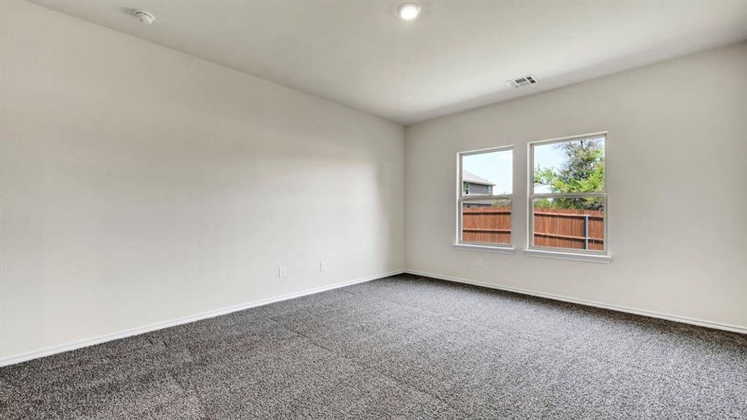 Spacious room featuring neutral carpeting, light-toned walls, and a pair of double-hung windows