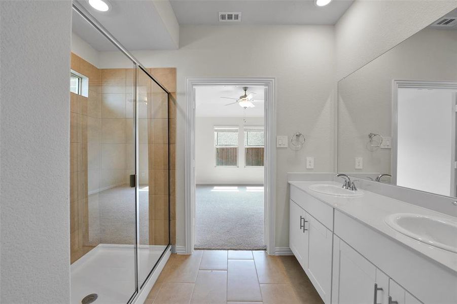 Full bathroom with a stall shower, double vanity, light tile patterned floors, ceiling fan, and recessed lighting Full bathroom with a stall shower, double vanity, light tile patterned floors, ceiling fan, and recessed lighting