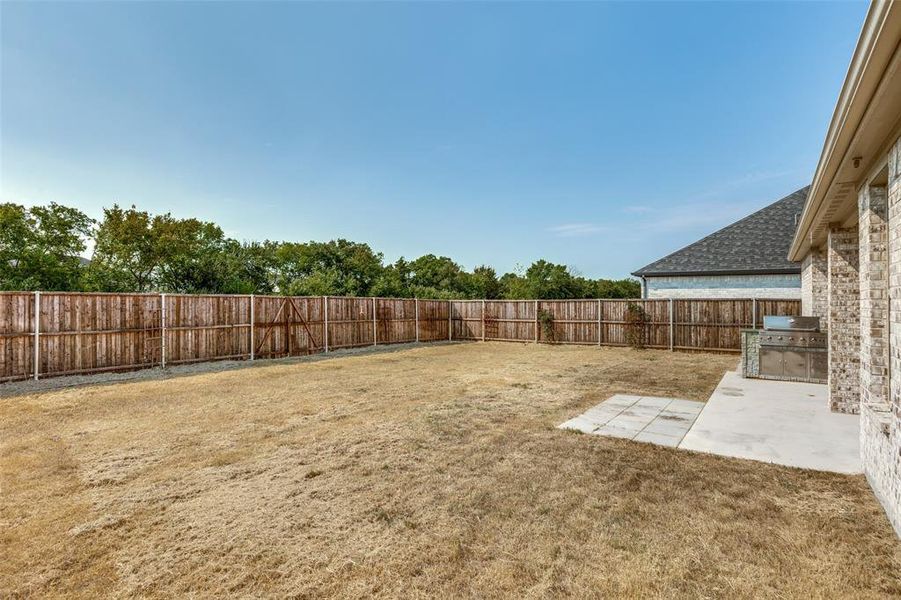 Fenced backyard with area for grilling and a patio area Fenced backyard with area for grilling and a patio area