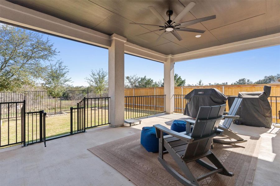 Fenced backyard with ceiling fan, a patio area, a grill, and a gate
