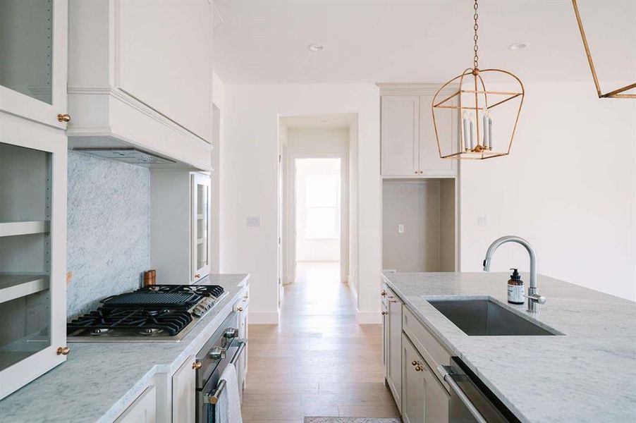 Kitchen with light stone countertops, appliances with stainless steel finishes, white cabinetry, and sink