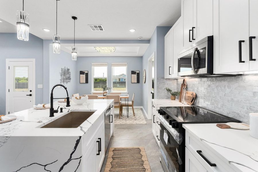 Kitchen featuring stainless steel appliances, white cabinetry, tasteful backsplash, decorative light fixtures, and recessed lighting Kitchen featuring stainless steel appliances, white cabinetry, tasteful backsplash, decorative light fixtures, and recessed lighting