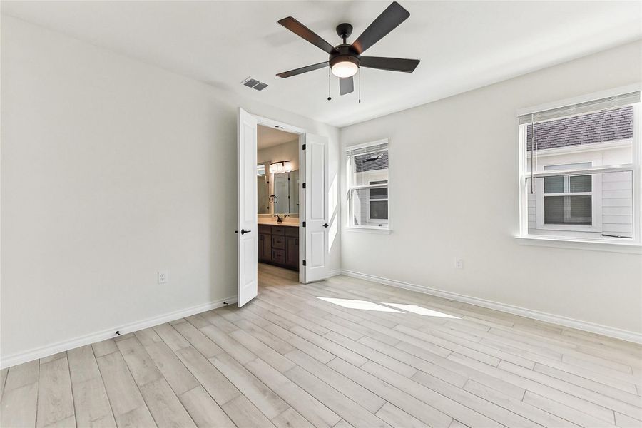 Unfurnished bedroom with visible vents, baseboards, light wood finished floors, and ensuite bathroom Unfurnished bedroom with visible vents, baseboards, light wood finished floors, and ensuite bathroom