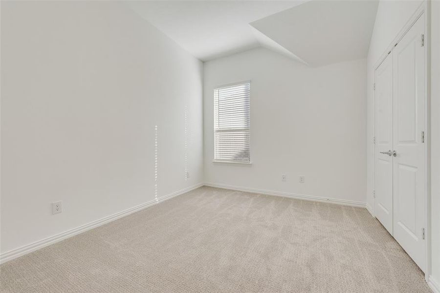 Unfurnished bedroom featuring light colored carpet and lofted ceiling