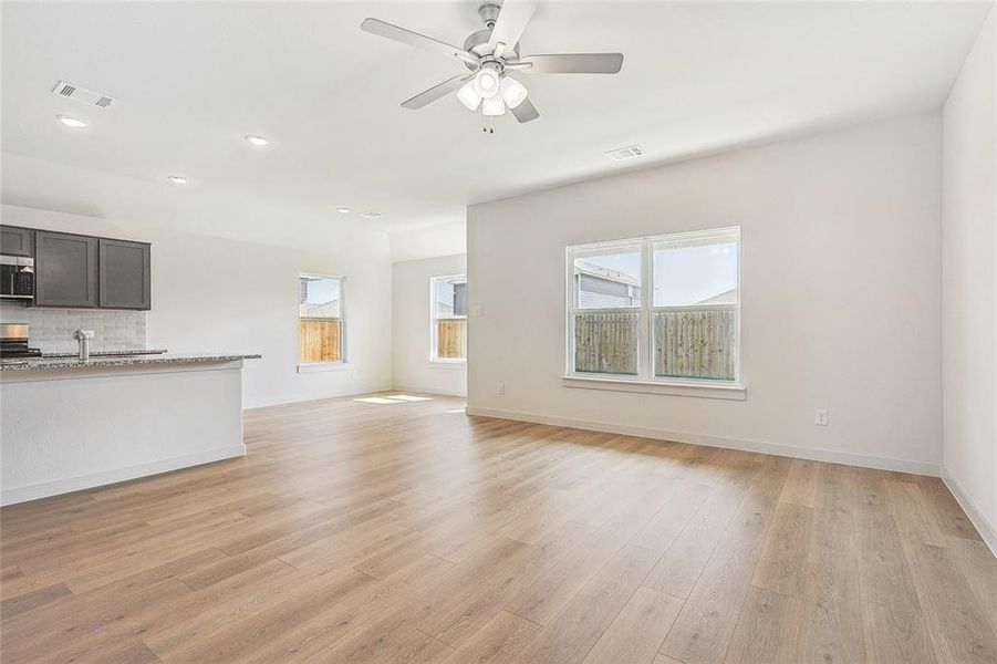 Unfurnished living room featuring ceiling fan, sink, and light hardwood / wood-style floors