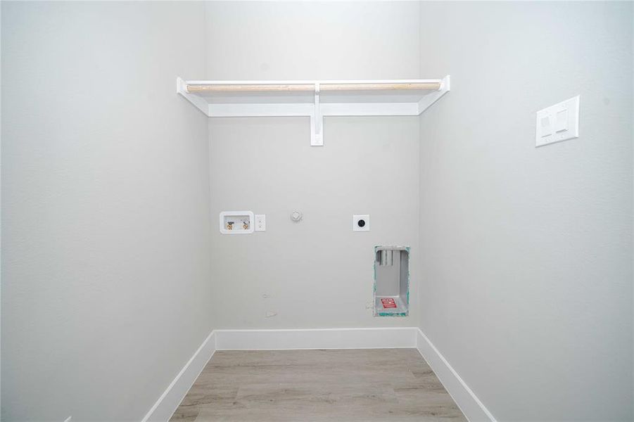 Laundry room featuring gas dryer hookup, light wood-style flooring, washer hookup, and electric dryer hookup Laundry room featuring gas dryer hookup, light wood-style flooring, washer hookup, and electric dryer hookup