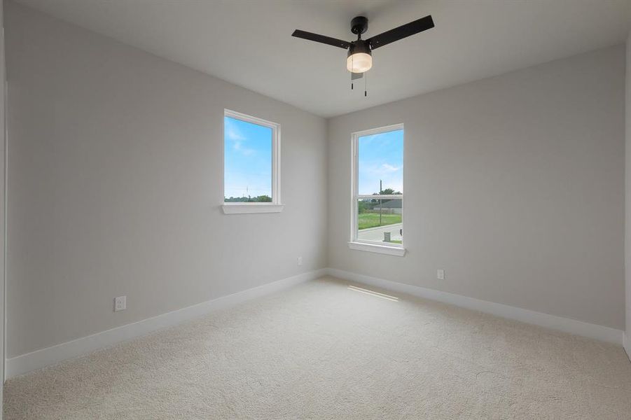 Spare room featuring light carpet, ceiling fan, and baseboards