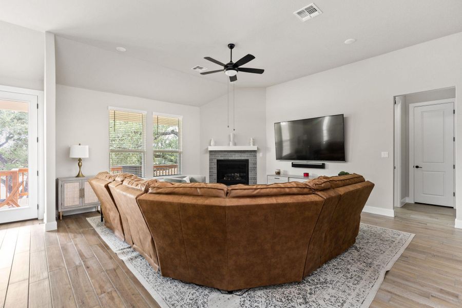 Living room with a brick fireplace, lofted ceiling, and a ceiling fan