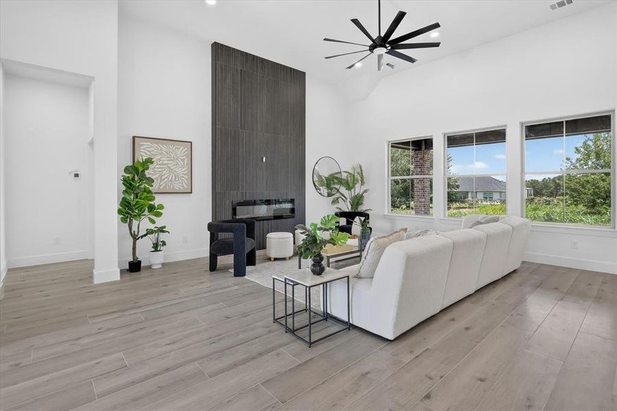 Spacious living area featuring a vaulted ceiling, wood-finish flooring, and a modern fireplace with a dark tile surround