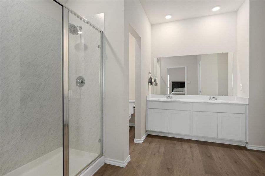Bathroom featuring a shower stall, dark wood-type flooring, and double vanity Bathroom featuring a shower stall, dark wood-type flooring, and double vanity
