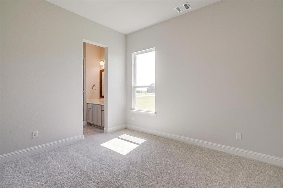 Unfurnished bedroom featuring light colored carpet and ensuite bathroom