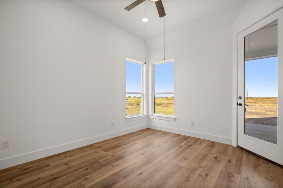 A well-lit room features durable wood flooring, soaring ceilings, and a glass paneled door opening to a private vista. A well-lit room features durable wood flooring, soaring ceilings, and a glass paneled door opening to a private vista.