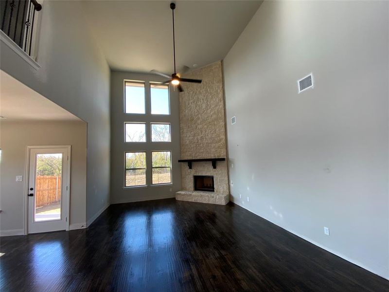 Family room offers a wall of windows to capture the Nature Area view, Stone fireplace, rich hardwoods, and a ceiling fan