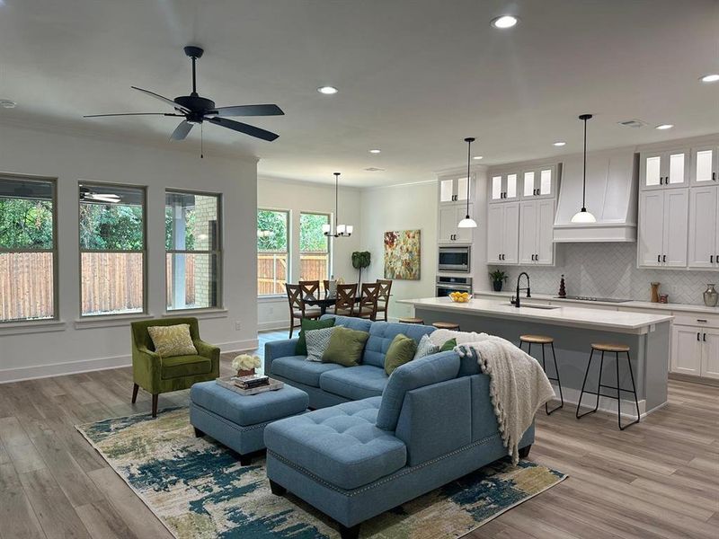 Living room featuring crown molding, sink, ceiling fan with notable chandelier, and light hardwood / wood-style floors