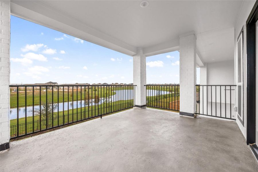Expansive second-story covered balcony offering a private outdoor oasis with spectacular panoramic views. This elevated retreat features clean concrete flooring, sturdy columns, and sleek black wrought-iron safety railings that maximize visibility. Positioned directly off the game room, it serves as the ultimate vantage point to enjoy peaceful morning coffee or gorgeous evening sunsets overlooking the community lake and neighborhood green spaces. Expansive second-story covered balcony offering a private outdoor oasis with spectacular panoramic views. This elevated retreat features clean concrete flooring, sturdy columns, and sleek black wrought-iron safety railings that maximize visibility. Positioned directly off the game room, it serves as the ultimate vantage point to enjoy peaceful morning coffee or gorgeous evening sunsets overlooking the community lake and neighborhood green spaces.