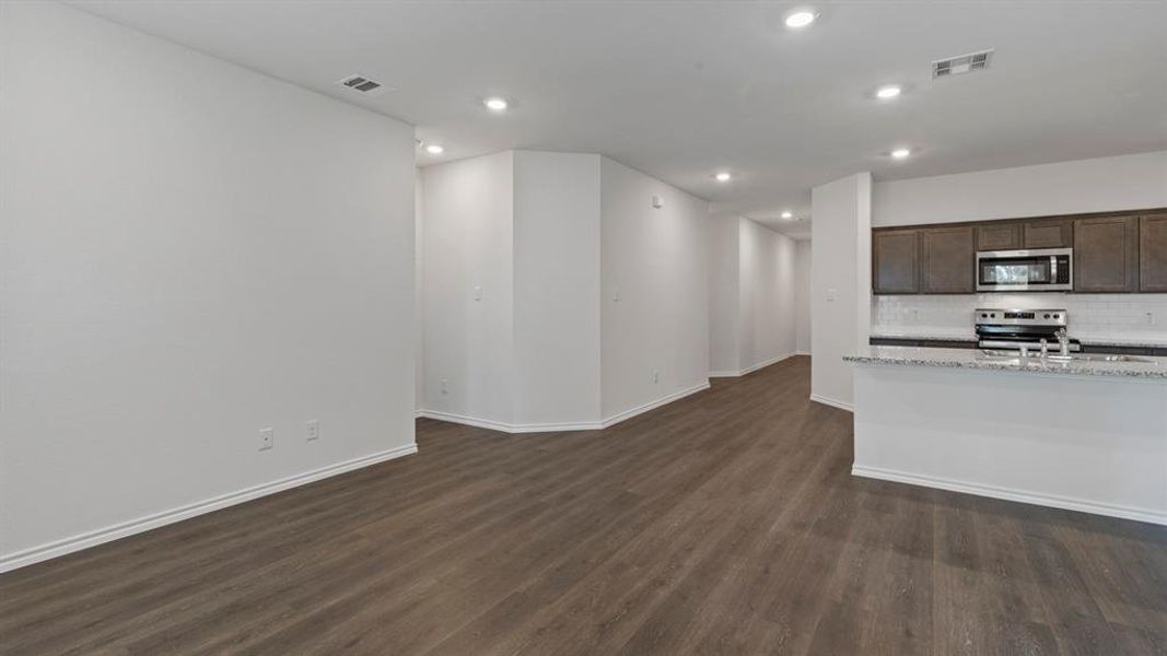 Kitchen featuring dark wood finish cabinetry, stainless steel appliances, dark wood-style flooring, backsplash, and recessed lighting