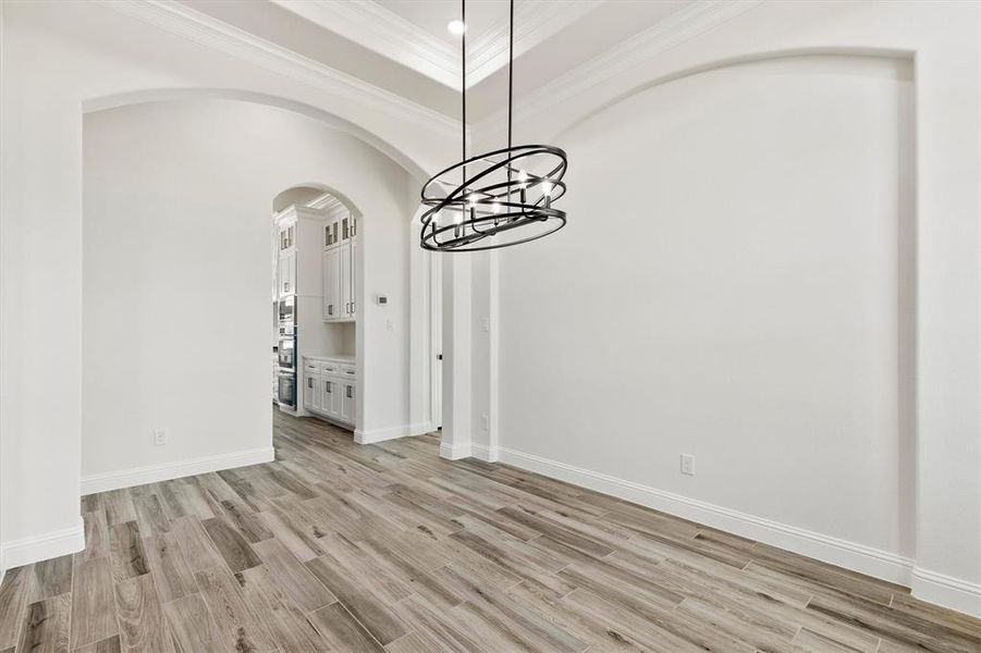 Dining area with light custom flooring and crown molding