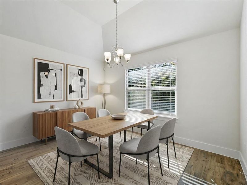 Vaulted ceiling dining area featuring wood-finish flooring, a contemporary chandelier, and a large window with blinds