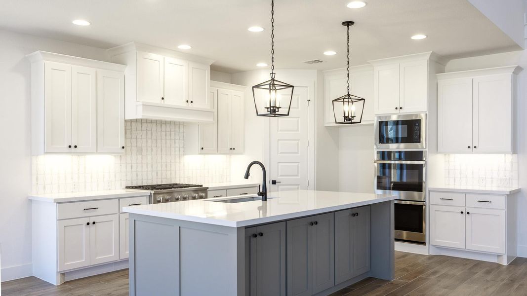 Kitchen with tasteful backsplash, dark wood finished floors, white cabinets, appliances with stainless steel finishes, and recessed lighting Kitchen with tasteful backsplash, dark wood finished floors, white cabinets, appliances with stainless steel finishes, and recessed lighting