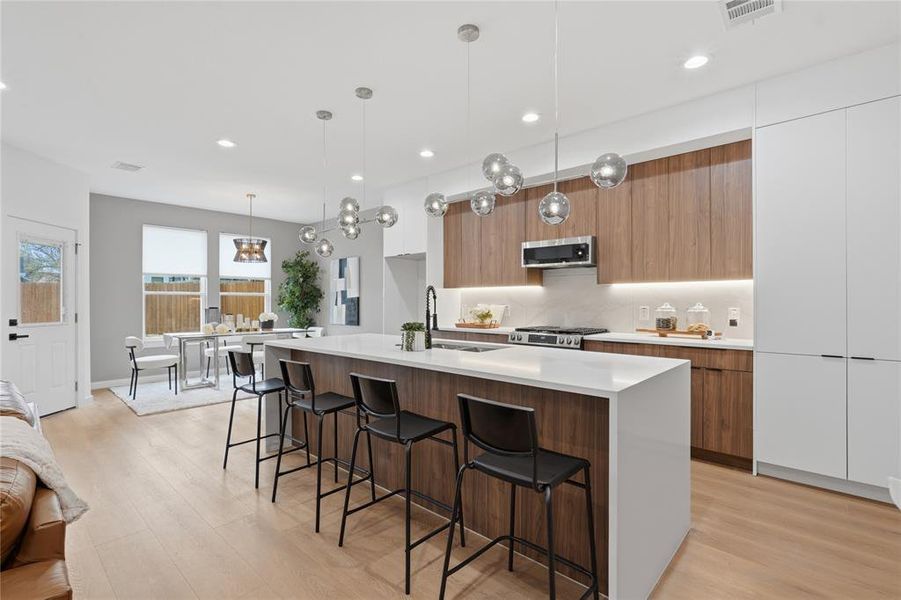 Kitchen with a breakfast bar, an island with sink, modern cabinets, wood finish cabinets, and light wood finished floors Kitchen with a breakfast bar, an island with sink, modern cabinets, wood finish cabinets, and light wood finished floors
