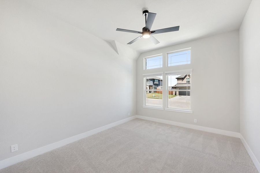 Empty bedroom with vaulted ceiling, ceiling fan, carpet flooring, and large corner windows