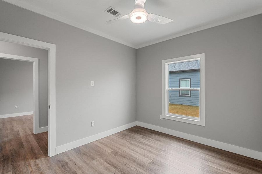 Spare room with light wood-style flooring, ornamental molding, and a ceiling fan