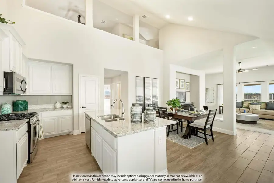Open-concept kitchen with white cabinets, granite island, and dining area under a two-story ceiling
