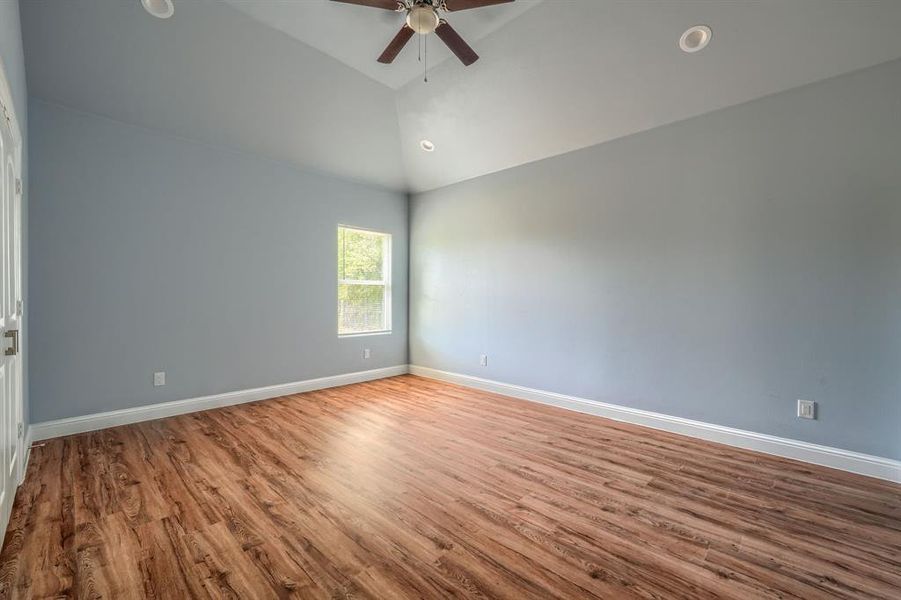 Empty room with high vaulted ceiling, ceiling fan, and hardwood / wood-style floors